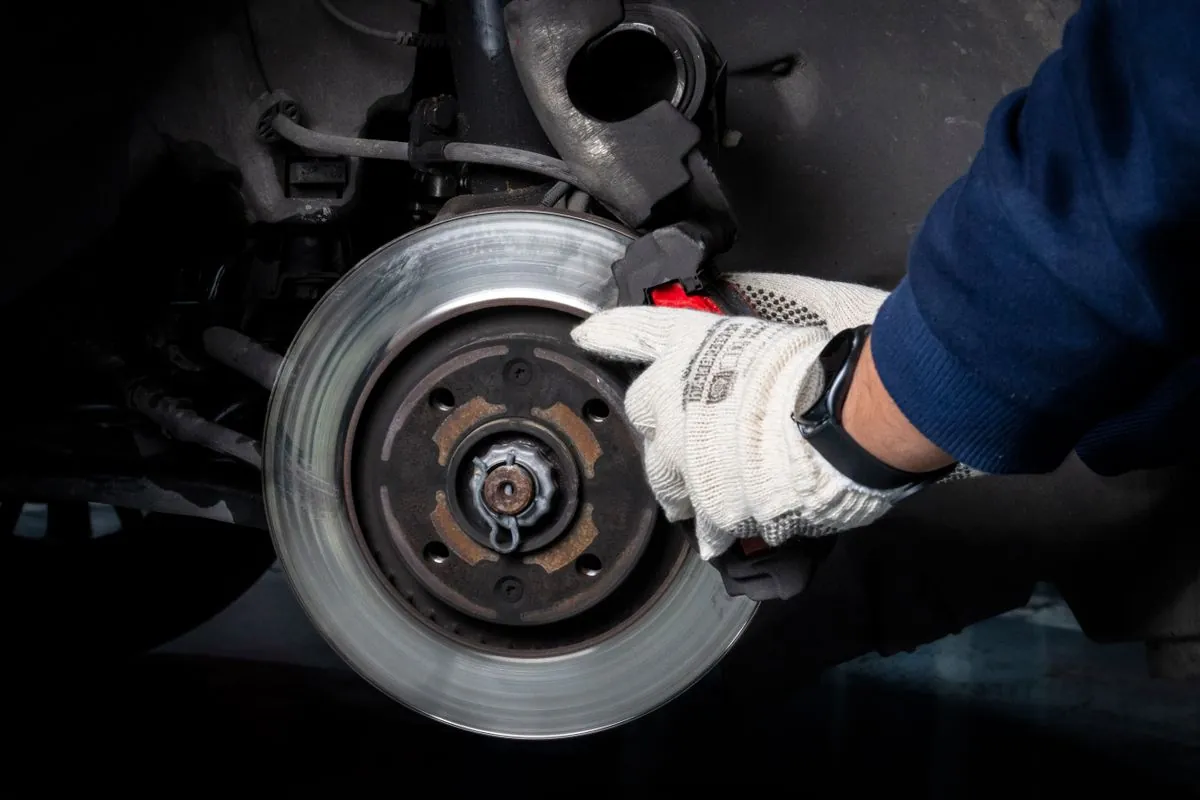 Arbeiten an Bremssattel und Bremsscheibe mit Schutzhandschuhen