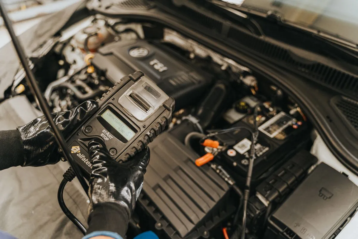 Prüfung der Fahrzeugbatterie mit einem Messgerät im Motorraum